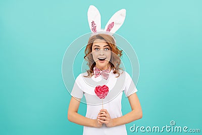 surprised easter girl wear bunny ears hold heart lollipop Stock Photo