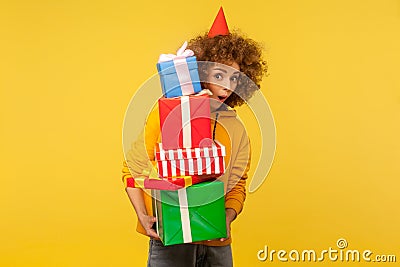 Surprised emotions from big mountain of gifts. Portrait of amazed woman with party cone holding present boxes Stock Photo