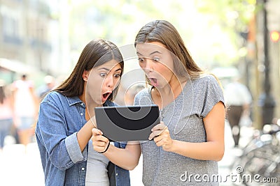 Surprised friends finding online content in the street Stock Photo