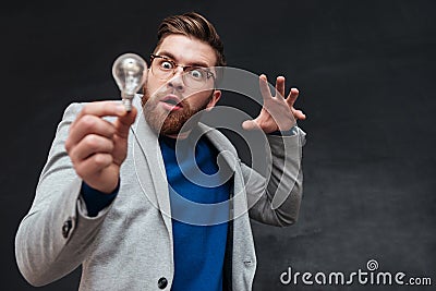 Surprised funnny bearded man in eyeglasses lights the bulb Stock Photo