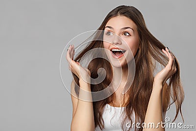 Surprised happy beautiful woman looking sideways in excitement. Isolated on gray background Stock Photo
