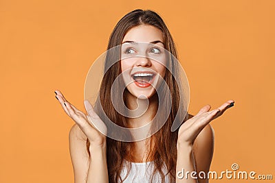 Surprised happy beautiful woman looking sideways in excitement. Isolated on orange background Stock Photo