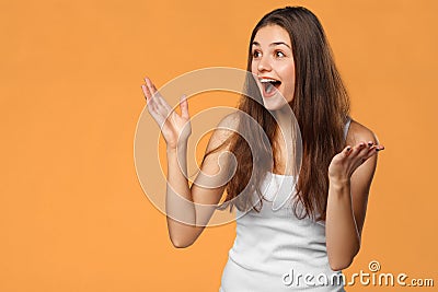 Surprised happy beautiful woman looking sideways in excitement, isolated on orange background Stock Photo