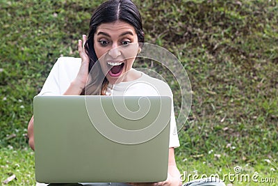 Surprised Hispanic woman using laptop in outdoors Stock Photo