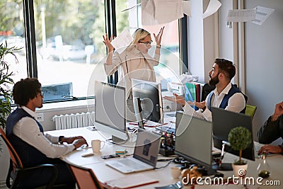 Surprised employee explaining to angry female boss who is throwing papers in the ear in front another employee. business, stress Stock Photo