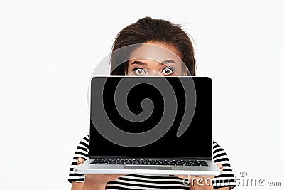 Surprised shocked african woman hiding behind blank screen laptop Stock Photo