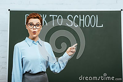 Surprised teacher pointing with finger near Stock Photo
