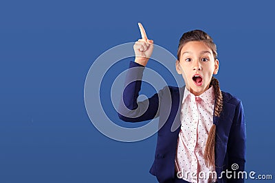Surprised teenage girl pointing her finger up on classic blue background Stock Photo