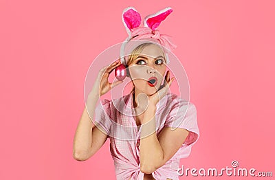 Surprised woman in bunny ears with pink eggs. Happy Easter. Hunting eggs. Amazed girl with colored egg. Spring holiday. Stock Photo