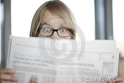 Surprised woman with glasses reading a newspaper Stock Photo