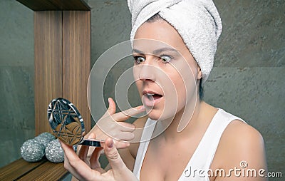Surprised woman looking an acne pimple in mirror Stock Photo