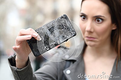 Surprised woman looking at her broken smart phone Stock Photo