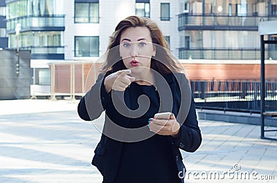 Surprised woman with a phone in her hand, saw something and shows a finger. concept of feelings and expression of human emotions Stock Photo