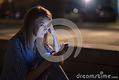 Surprised and worried young woman getting bad news on smartphone Stock Photo