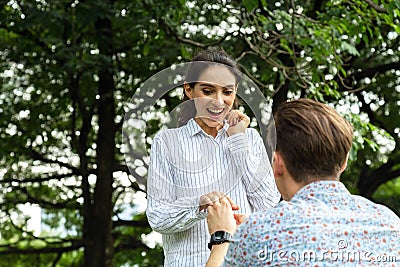 Surprised young woman and smiling while her boyfriend marriage proposing in the park. marry me. love, couple, date, wedding - Stock Photo