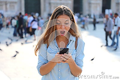 Surprised young woman using smart phone outdoors. Close up portrait surprised screaming girl looking at phone seeing news or Stock Photo