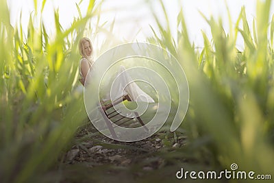 a miniature woman resting sitting among gigantic tufts of grass Stock Photo