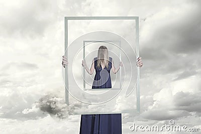 Surreal image of a woman holding a frame that reflects herself Stock Photo