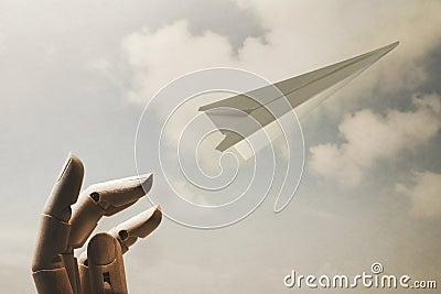 Surreal image of a wooden hand that launches a paper airplane in the sky Stock Photo