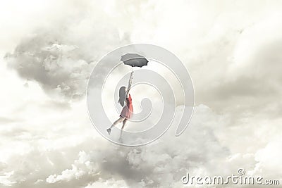 Surreal moment of an elegant woman flying in the middle of the clouds hanging on her umbrella Stock Photo