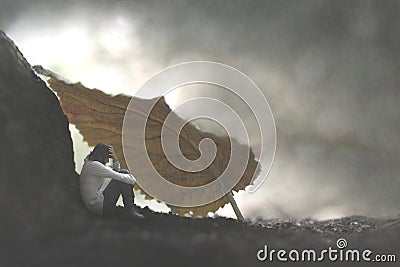 Surreal moment of a small woman who protects herself from the rain by sheltering herself under a leaf Stock Photo