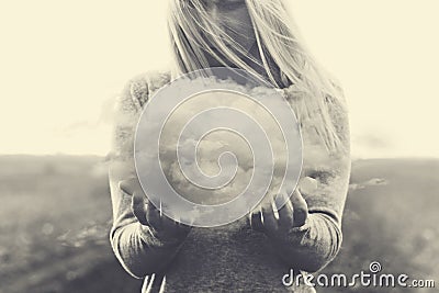 A surreal moment, solitary woman holding in her hands a grey cloud Stock Photo