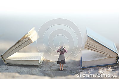 Surreal moment where a small woman stops her ears so as not to listen to two giant talking books Stock Photo