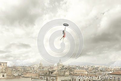 Surreal moment of a woman flying with her umbrella over the city Stock Photo