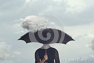 Surreal moment of a woman hiding under the umbrella from a small cloud that chases her Stock Photo