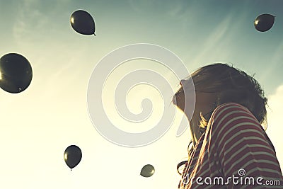 Surreal moment, woman looking surprised with a rain of black balls falling from the sky Stock Photo