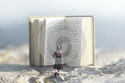 Surreal moment of a woman walking towards a giant book Stock Photo