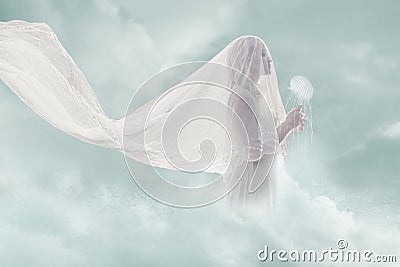 Surreal portrait of bride in clouds hold jellyfish Stock Photo