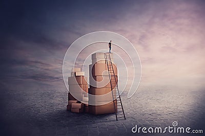 Surreal scene as a minuscule man wanderer standing on a stack of cardboard boxes, holding hand to forehead looking at the horizon Stock Photo