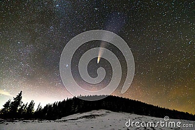 Surreal view of night in mountains with starry dark blue cloudy sky and C/2020 F3 NEOWISE comet with light tail Stock Photo