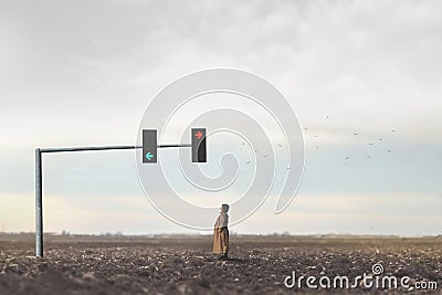 surreal woman observes the arrows of a traffic light in the middle of the desert, concept of choosing a direction in life Stock Photo