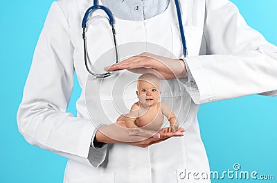 Surrogacy concept. Doctor holding cute little baby on blue background, closeup Stock Photo