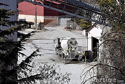 worker cleaning cement truck with hose after transporting cement in factory yard Stock Photo