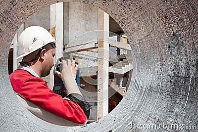 Surveyor engineer is measuring level on construction site. Surveyors ensure precise measurements before undertaking large Stock Photo