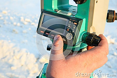 Surveyor`s finger presses the button on the total station Stock Photo