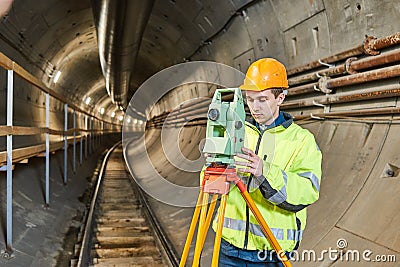 Surveyor with theodolite level at underground railway tunnel construction work Stock Photo