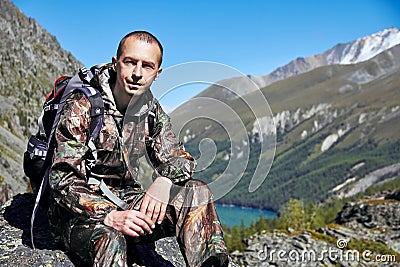 Survival in the wild. A man in camouflage resting among the mountains. Stalker, survive in the woods Editorial Stock Photo