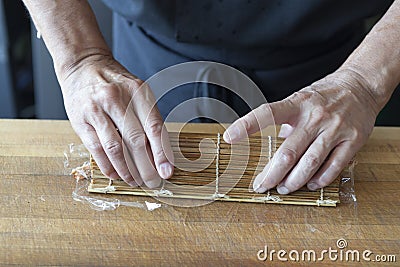 Sushi chef rolling up sushi in a mat Stock Photo