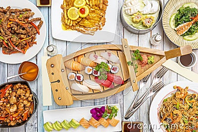 Sushi and Chinese food plates viewed from above, minced chicken fillets in lemon sauce. Bluefin tuna, butterfish, Norwegian salmon Stock Photo