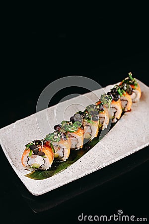 Sushi Chuka Roll on a white plate on a black background Stock Photo