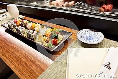 Sushi in Japanese Food Restaurant â€“ Kitchen Serving Background, Plate with Soy Sauce, Row of Nigiri and Rolls with Wasabi Stock Photo