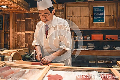 Sushi master chef preparing fresh tuna sashimi breakfast at the Tsukiji fish market in Tokyo Editorial Stock Photo