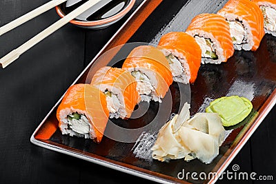 Sushi Roll - Maki Sushi made of salmon, cucumber, avocado and cream cheese on dark wooden background. Stock Photo