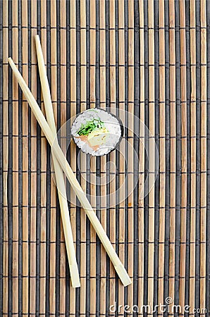 Sushi roll and wooden chopsticks lie on a bamboo straw serwing mat. Traditional Asian food. Top view. Flat lay minimalism shot Stock Photo