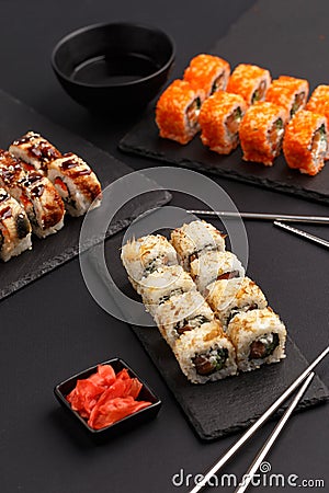 Sushi rolls on colored plates on a black background. A look from above Stock Photo