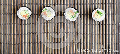 Sushi rolls lies on a bamboo straw serwing mat. Traditional Asian food. Top view. Flat lay minimalism shot with copy space Stock Photo